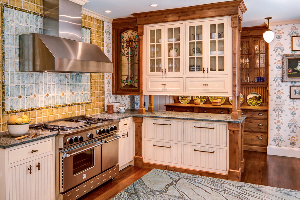 Diseño de cocina clásica con armarios tipo vitrina, puertas de armario blancas, salpicadero multicolor y electrodomésticos de acero inoxidable