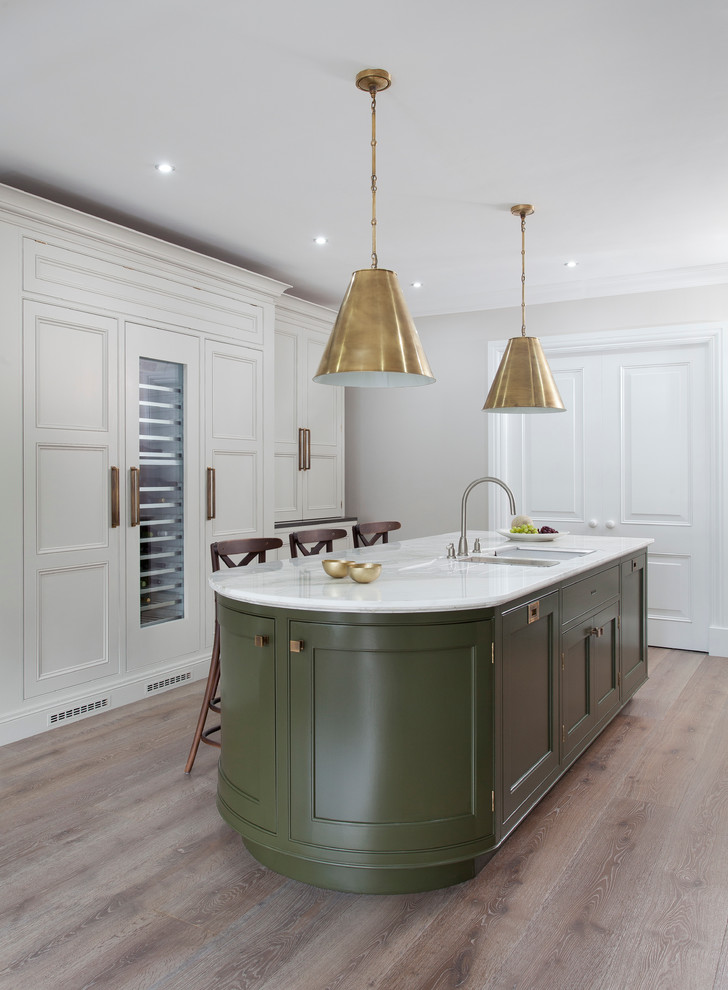 Large contemporary galley kitchen in Dublin with a submerged sink, beaded cabinets, marble worktops, stainless steel appliances, light hardwood flooring and an island.