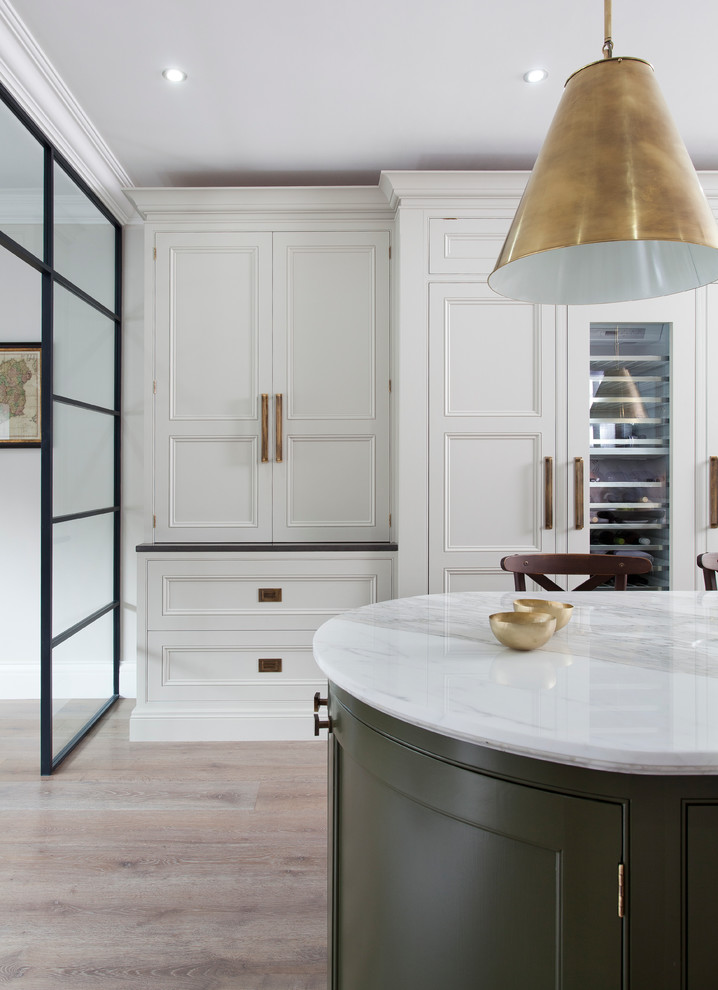 Cette photo montre une cuisine parallèle tendance avec un évier encastré, un placard à porte affleurante, plan de travail en marbre, un électroménager en acier inoxydable, parquet clair et îlot.