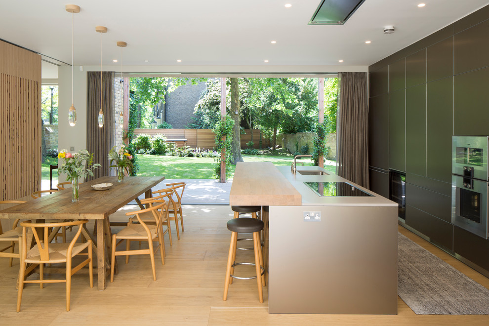 Photo of a modern kitchen/diner in London with a submerged sink, light hardwood flooring, an island, beige floors and white worktops.
