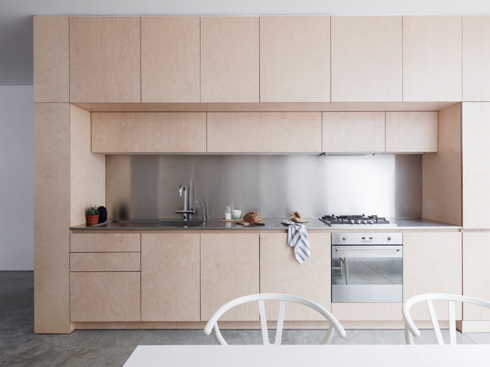 Inredning av ett modernt grå linjärt grått kök och matrum, med en integrerad diskho, släta luckor, skåp i ljust trä, stänkskydd med metallisk yta, rostfria vitvaror, betonggolv och grått golv