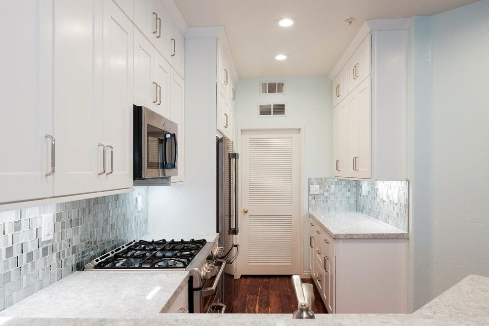 Small trendy galley medium tone wood floor and brown floor eat-in kitchen photo in Orange County with a drop-in sink, shaker cabinets, white cabinets, quartz countertops, blue backsplash, glass tile backsplash, stainless steel appliances and no island