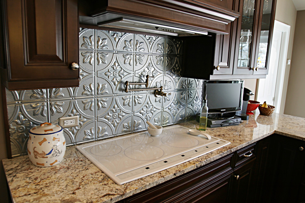 Immagine di una cucina classica con lavello stile country, ante con bugna sagomata, ante in legno bruno, top in granito, pavimento in legno massello medio e penisola