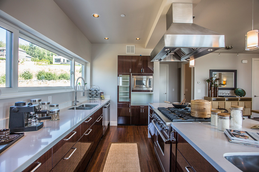 シアトルにあるコンテンポラリースタイルのおしゃれなキッチン (ダブルシンク、フラットパネル扉のキャビネット、濃色木目調キャビネット、シルバーの調理設備) の写真