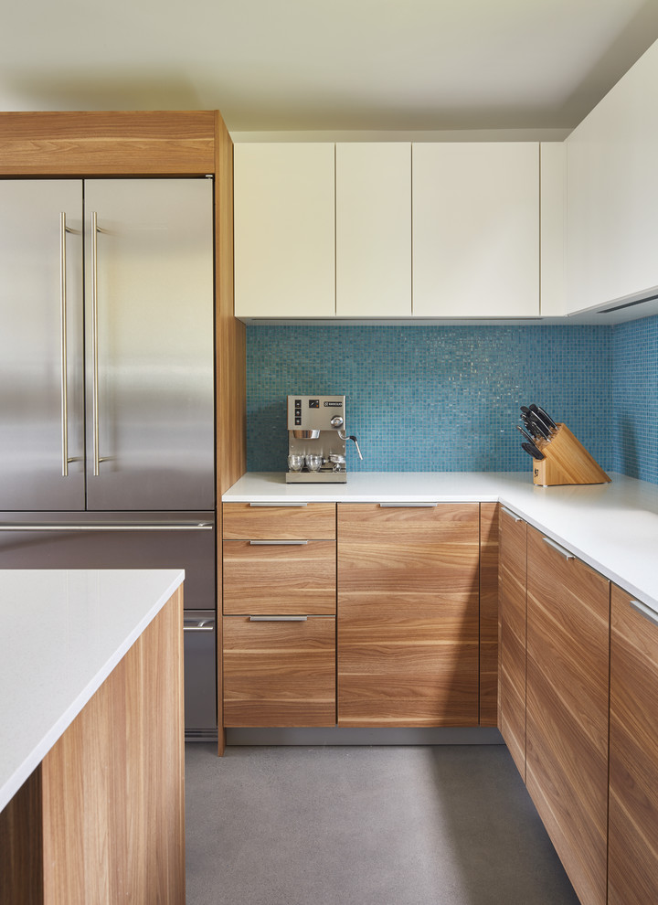 シアトルにあるお手頃価格のコンテンポラリースタイルのおしゃれなキッチン (シングルシンク、フラットパネル扉のキャビネット、中間色木目調キャビネット、クオーツストーンカウンター、青いキッチンパネル、ガラスタイルのキッチンパネル、シルバーの調理設備、コンクリートの床、グレーの床、白いキッチンカウンター) の写真