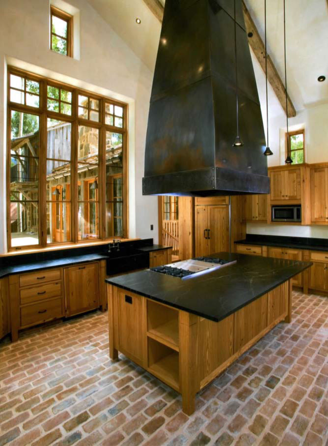 Bild på ett stort amerikanskt kök, med en rustik diskho, skåp i mellenmörkt trä, bänkskiva i täljsten, tegelgolv, en köksö, luckor med upphöjd panel, beige stänkskydd, stänkskydd i keramik och rostfria vitvaror