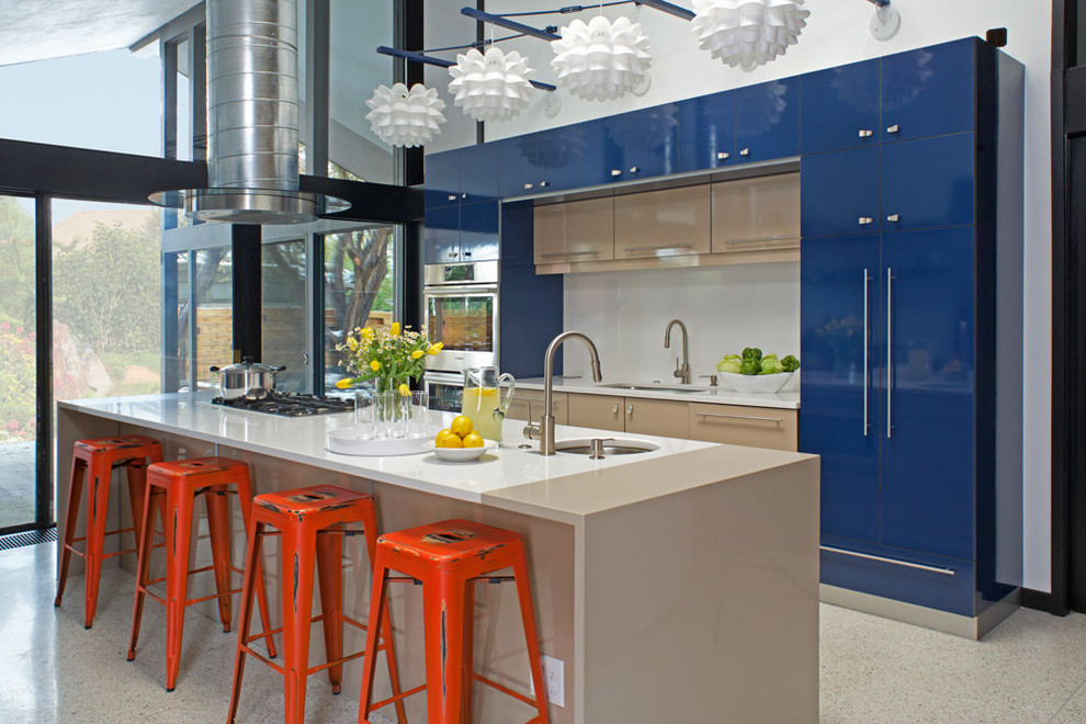 Ejemplo de cocina contemporánea con fregadero bajoencimera, armarios con paneles lisos, puertas de armario azules, salpicadero blanco, electrodomésticos de acero inoxidable y una isla