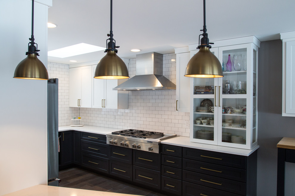 Enclosed kitchen - mid-sized transitional u-shaped dark wood floor enclosed kitchen idea in Portland with a farmhouse sink, flat-panel cabinets, blue cabinets, quartz countertops, white backsplash, subway tile backsplash, stainless steel appliances and a peninsula