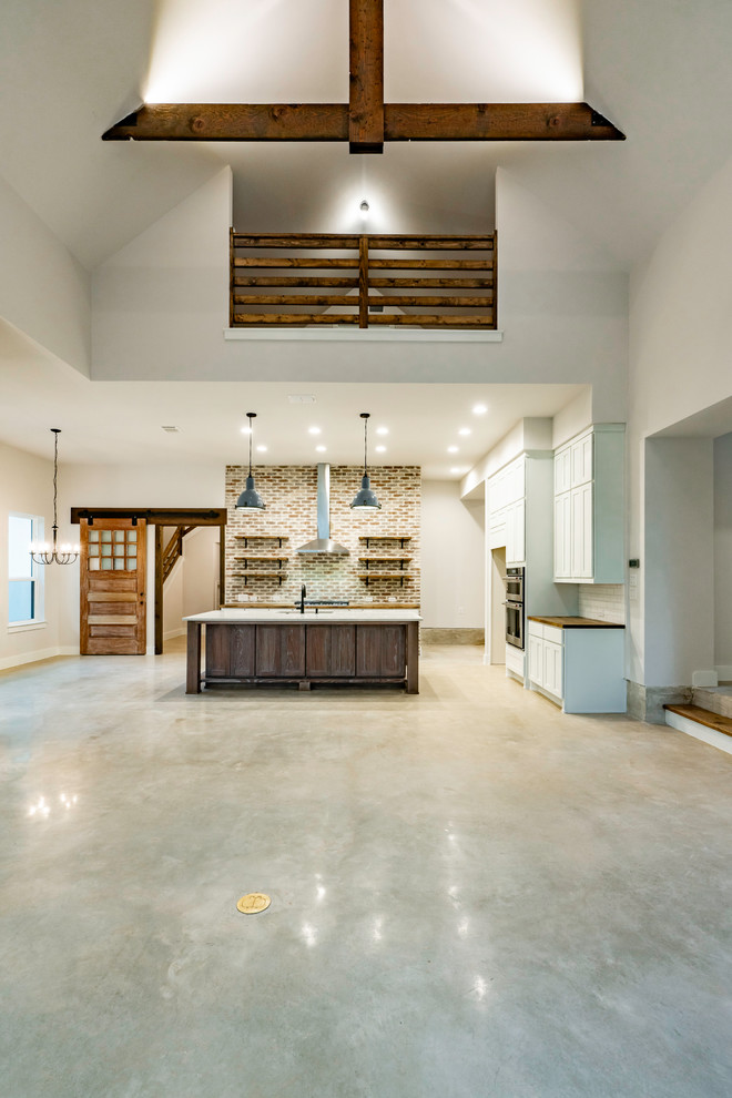 Large farmhouse u-shaped concrete floor and gray floor eat-in kitchen photo in Austin with an undermount sink, recessed-panel cabinets, white cabinets, wood countertops, red backsplash, brick backsplash, stainless steel appliances, an island and brown countertops