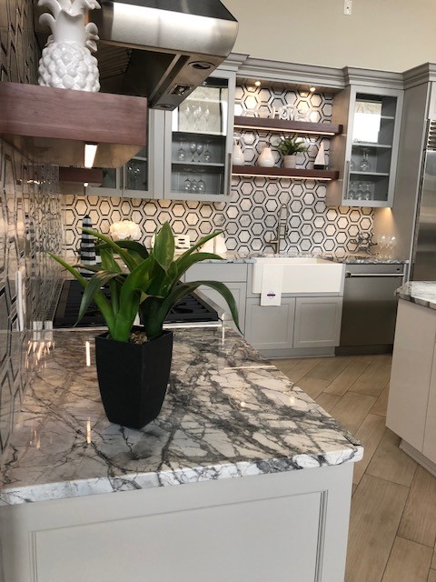 Inspiration for a medium sized contemporary l-shaped kitchen pantry in Richmond with a belfast sink, recessed-panel cabinets, white cabinets, marble worktops, grey splashback, mosaic tiled splashback, stainless steel appliances, light hardwood flooring, an island and beige floors.