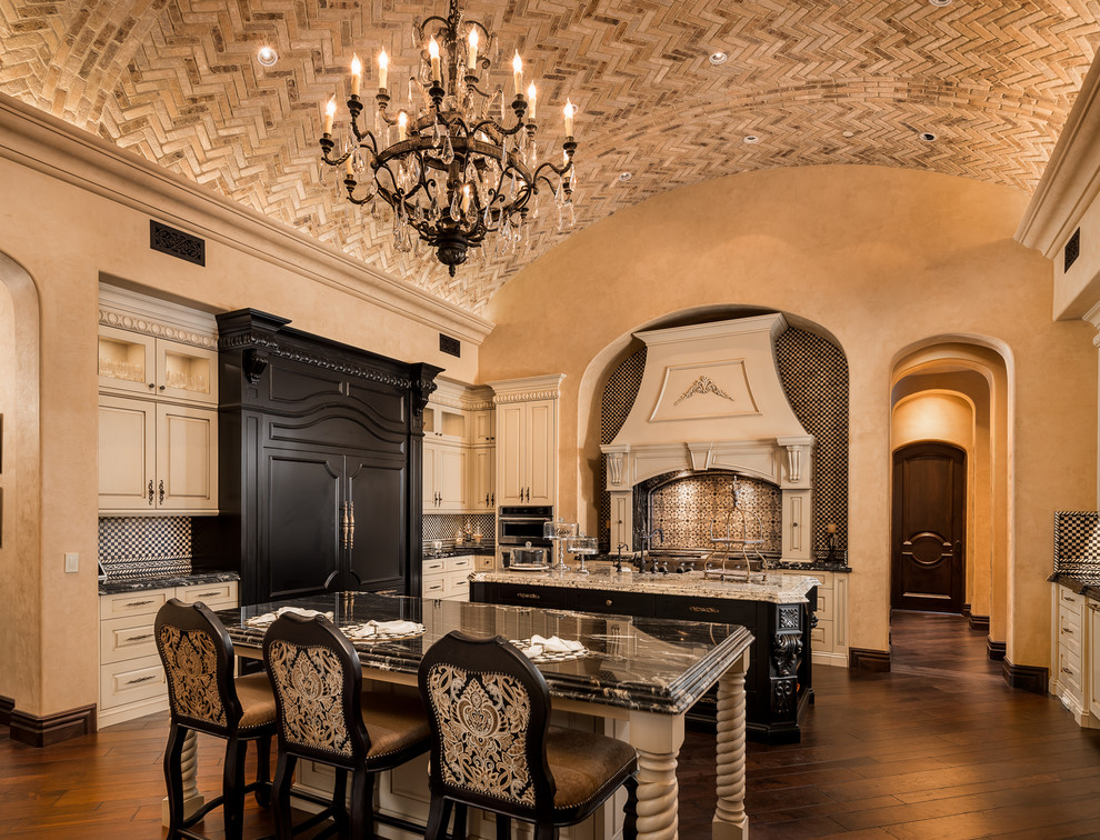 Huge tuscan u-shaped dark wood floor, brown floor and vaulted ceiling enclosed kitchen photo in Phoenix with a drop-in sink, flat-panel cabinets, white cabinets, granite countertops, subway tile backsplash, stainless steel appliances and two islands