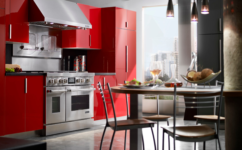 На фото: кухня среднего размера в современном стиле с обеденным столом, плоскими фасадами, красными фасадами и техникой из нержавеющей стали с