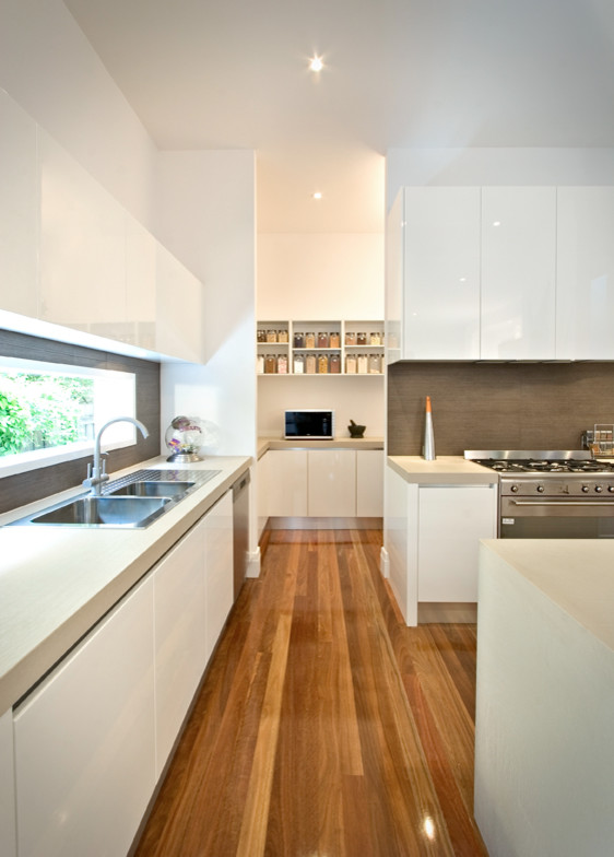 Inspiration for a mid-sized contemporary kitchen remodel in Melbourne with white cabinets, quartz countertops and an island
