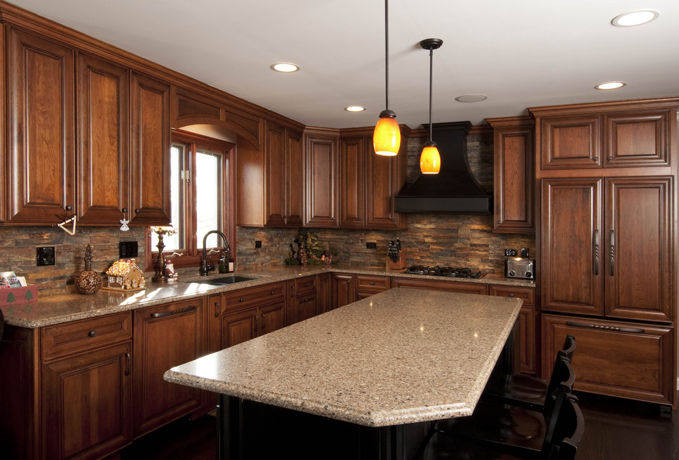 Bild på ett avskilt, mellanstort vintage l-kök, med en undermonterad diskho, luckor med upphöjd panel, skåp i mellenmörkt trä, granitbänkskiva, brunt stänkskydd, stänkskydd i stenkakel, integrerade vitvaror, mörkt trägolv, en köksö och brunt golv