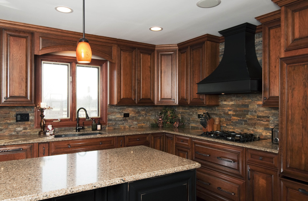 Inspiration for a mid-sized timeless l-shaped dark wood floor and brown floor enclosed kitchen remodel in Chicago with an undermount sink, raised-panel cabinets, medium tone wood cabinets, granite countertops, brown backsplash, stone tile backsplash, paneled appliances and an island