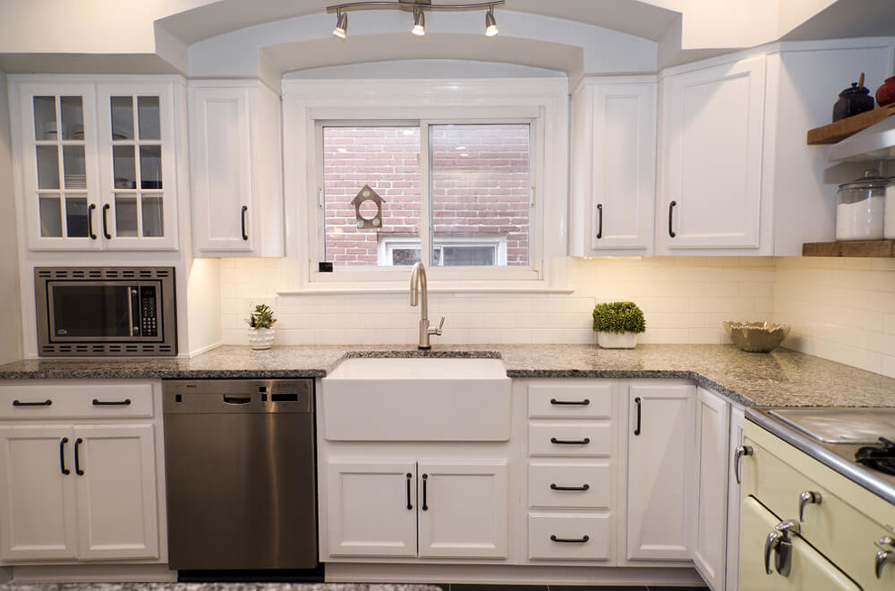 Small minimalist l-shaped porcelain tile and gray floor enclosed kitchen photo in Baltimore with a farmhouse sink, recessed-panel cabinets, white cabinets, granite countertops, yellow backsplash, ceramic backsplash, stainless steel appliances and a peninsula