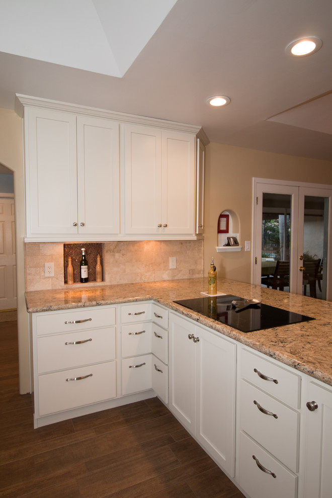 Example of a classic u-shaped porcelain tile eat-in kitchen design in Other with an undermount sink, shaker cabinets, white cabinets, quartz countertops, beige backsplash, subway tile backsplash and stainless steel appliances