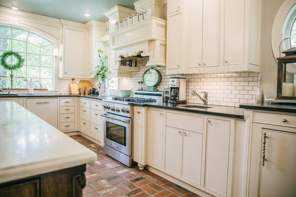 Inspiration for a mid-sized farmhouse u-shaped brick floor and brown floor kitchen remodel in Oklahoma City with an undermount sink, flat-panel cabinets, white cabinets, quartz countertops, white backsplash, subway tile backsplash, paneled appliances, an island and white countertops