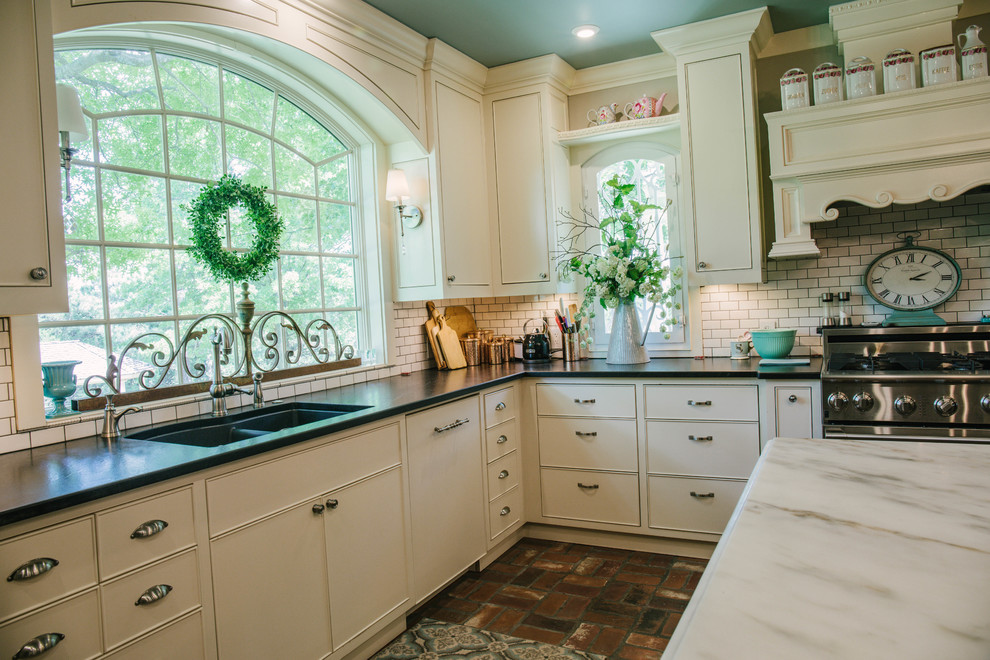 Bild på ett mellanstort lantligt vit vitt u-kök, med en undermonterad diskho, släta luckor, vita skåp, bänkskiva i kvarts, vitt stänkskydd, stänkskydd i tunnelbanekakel, integrerade vitvaror, tegelgolv, en köksö och brunt golv