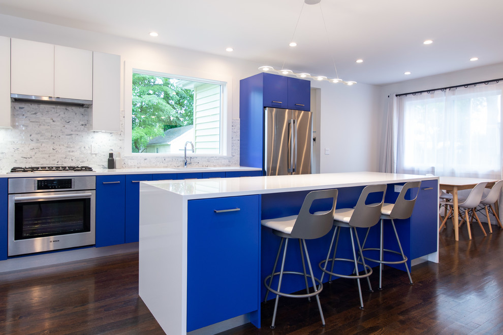 This is an example of a medium sized contemporary kitchen/diner in Other with flat-panel cabinets, blue cabinets, quartz worktops, marble splashback, stainless steel appliances, dark hardwood flooring, an island, white worktops, multi-coloured splashback and brown floors.