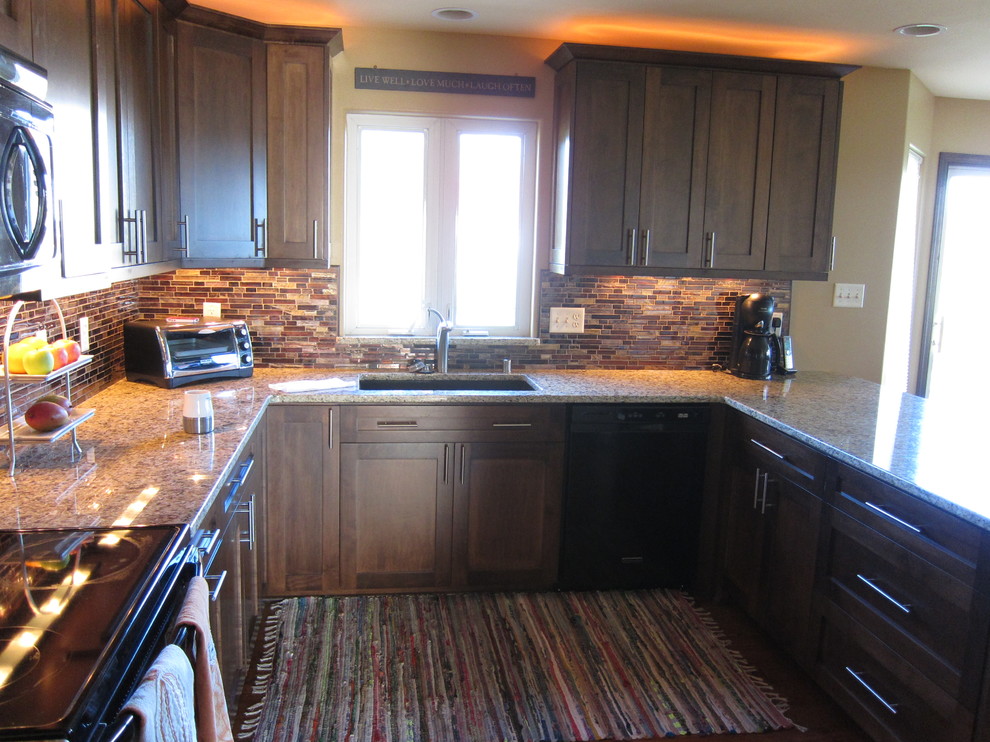 This is an example of a large traditional u-shaped open plan kitchen in Milwaukee with a submerged sink, shaker cabinets, dark wood cabinets, granite worktops, multi-coloured splashback, black appliances and medium hardwood flooring.