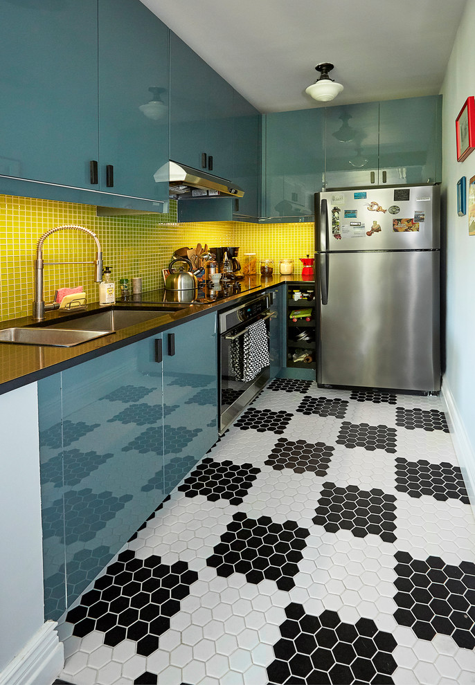 ニューヨークにあるお手頃価格の小さな北欧スタイルのおしゃれなキッチン (エプロンフロントシンク、フラットパネル扉のキャビネット、青いキャビネット、ガラスカウンター、緑のキッチンパネル、モザイクタイルのキッチンパネル、シルバーの調理設備、磁器タイルの床、白い床、黒いキッチンカウンター) の写真
