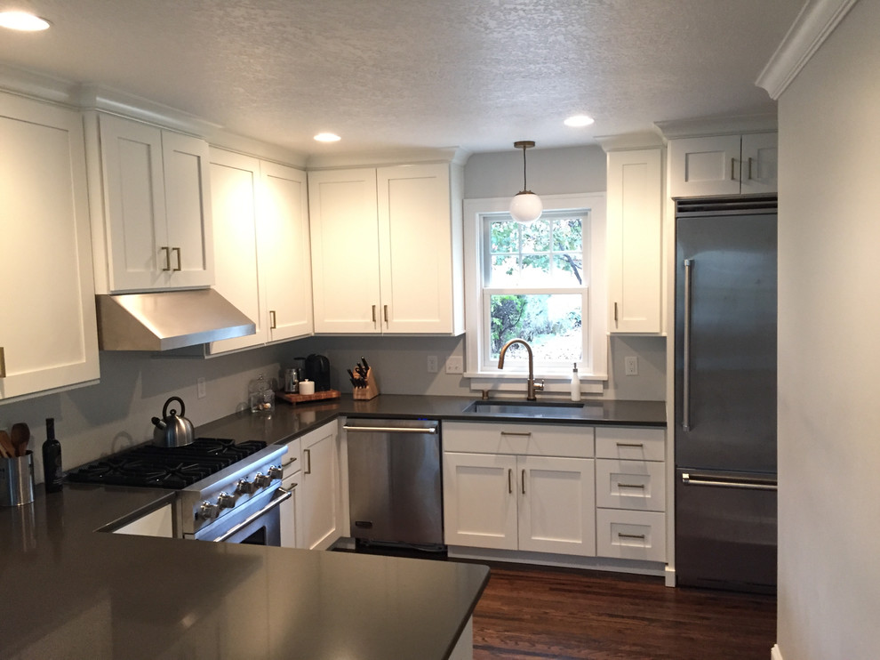 Foto på ett litet amerikanskt grå kök, med en undermonterad diskho, skåp i shakerstil, vita skåp, bänkskiva i kvarts, rostfria vitvaror, mörkt trägolv, en halv köksö och brunt golv