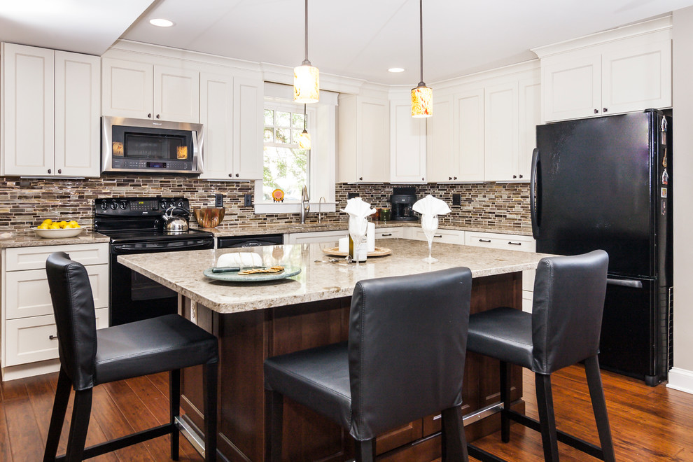 Amerikansk inredning av ett mellanstort kök, med luckor med infälld panel, vita skåp, granitbänkskiva, brunt stänkskydd, stänkskydd i glaskakel, svarta vitvaror, bambugolv, en köksö och en nedsänkt diskho