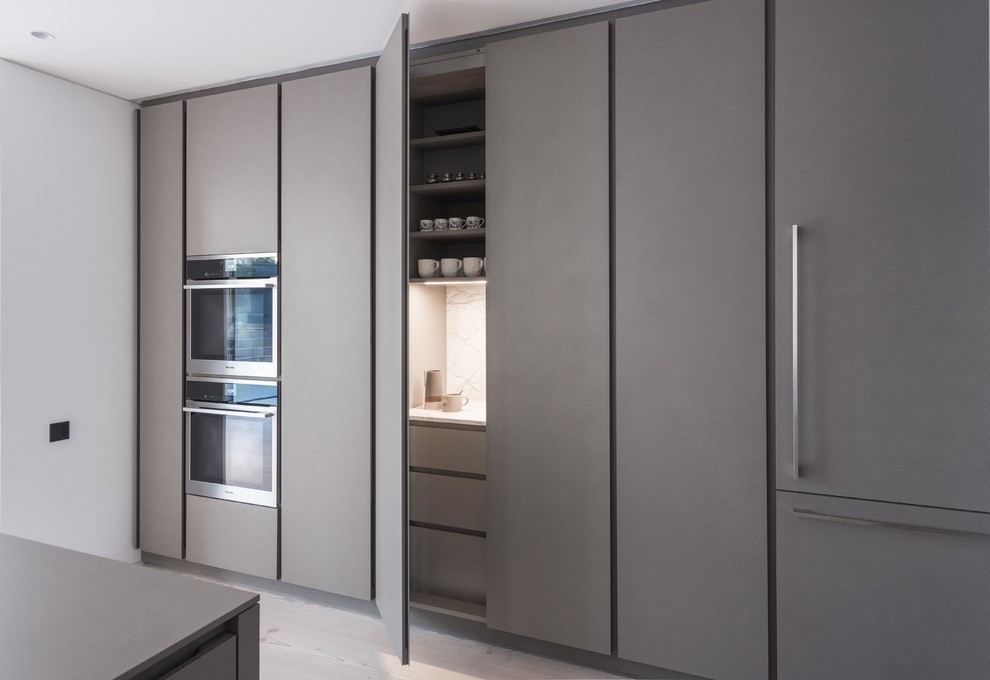 Ejemplo de cocina contemporánea grande con fregadero integrado, armarios con paneles lisos, puertas de armario grises, suelo de madera clara y una isla
