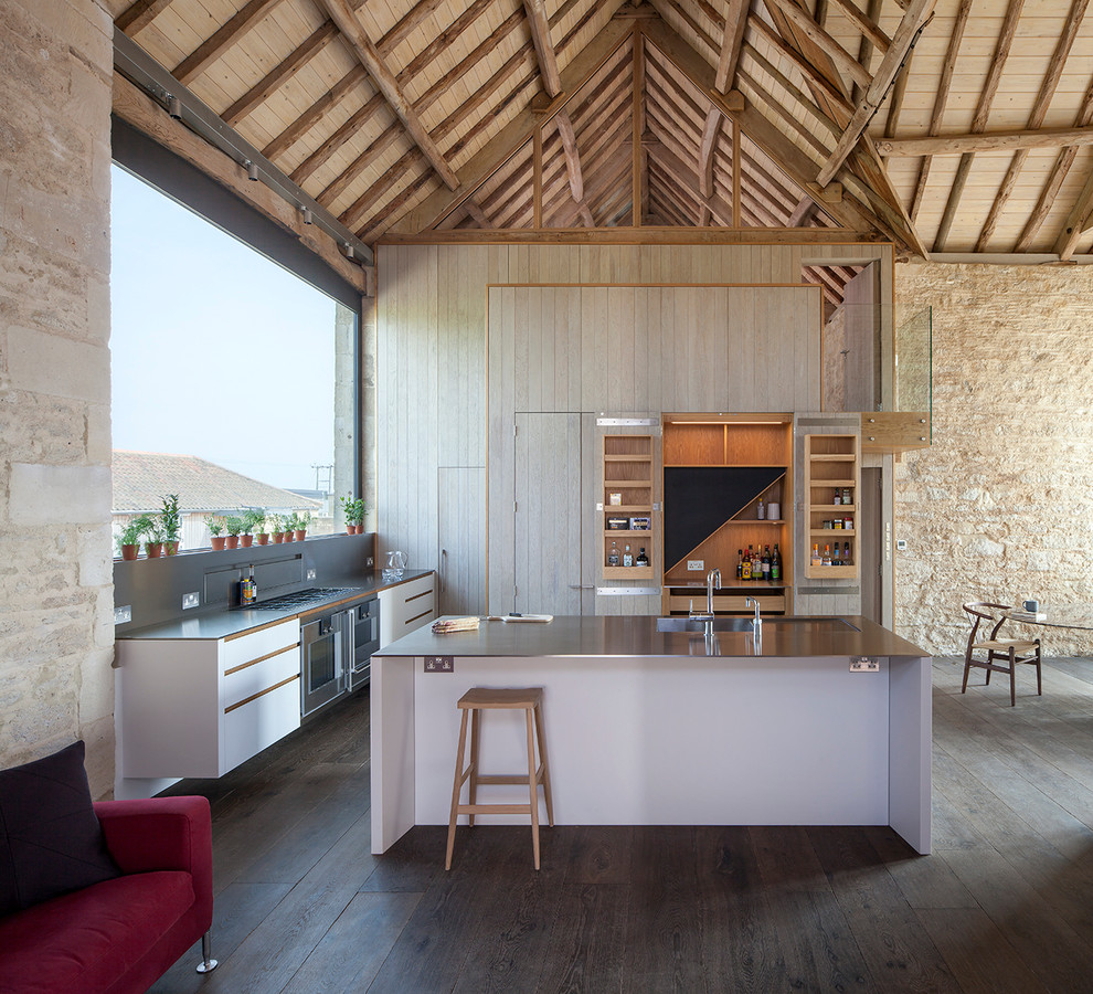 Exemple d'une cuisine ouverte nature en bois clair avec un plan de travail en inox, îlot, un évier intégré et parquet foncé.