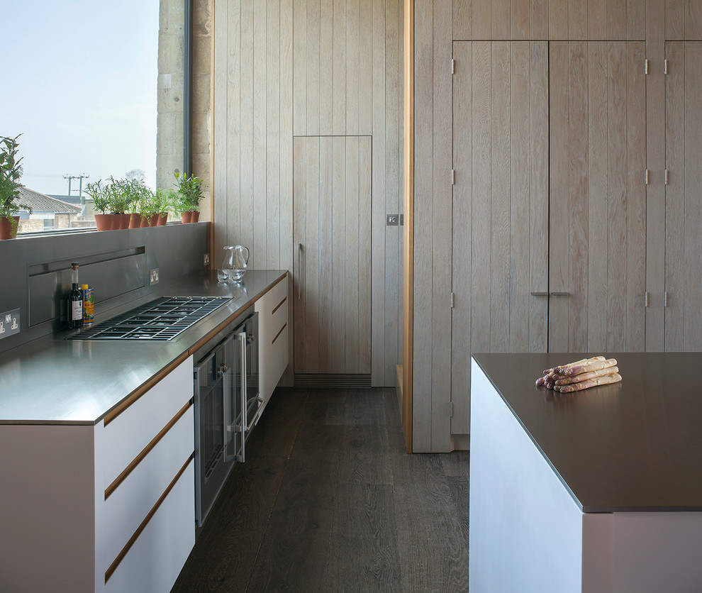 Foto på ett funkis kök med öppen planlösning, med skåp i slitet trä, bänkskiva i rostfritt stål och en köksö