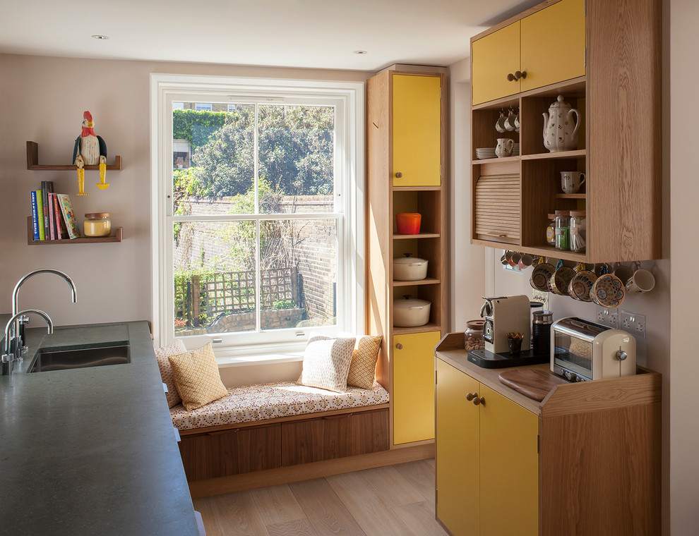 Photo of a retro kitchen in London with flat-panel cabinets.