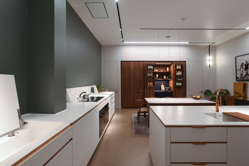 This is an example of a medium sized contemporary kitchen/diner in London with flat-panel cabinets, white cabinets, black appliances and an island.