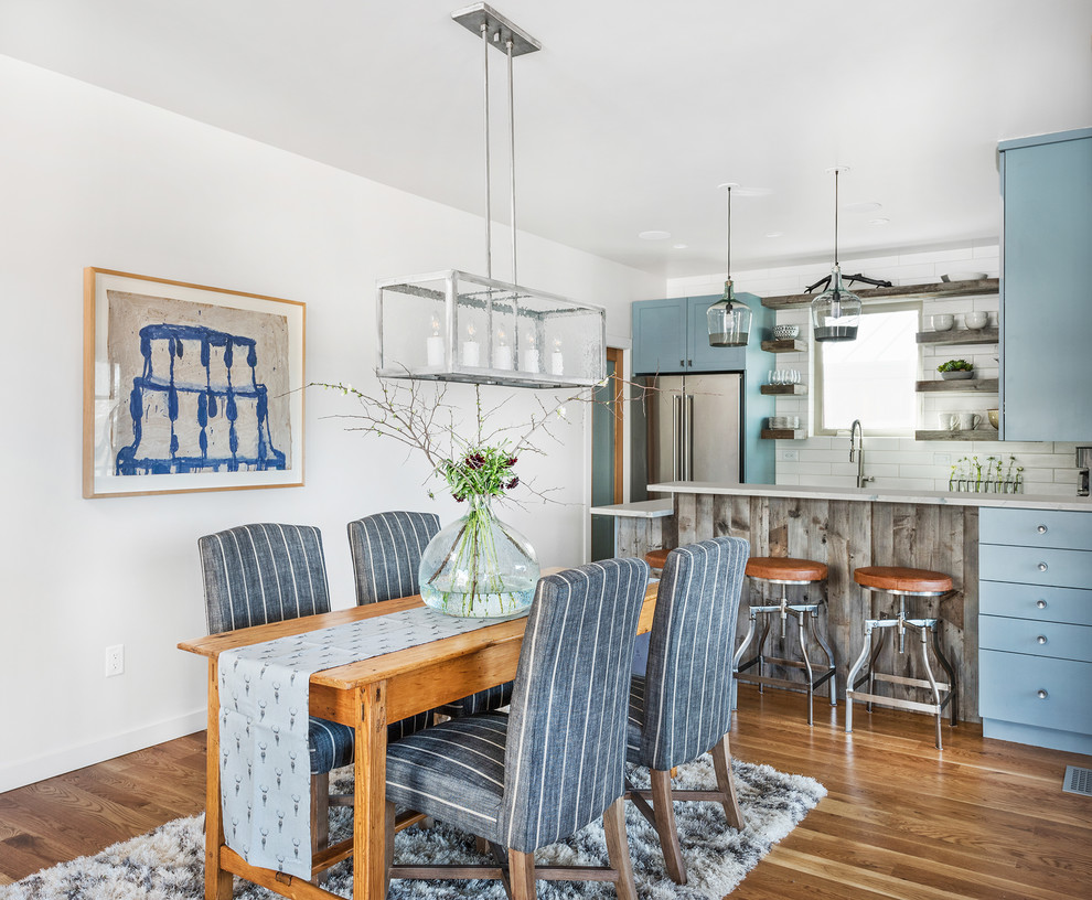 Bild på ett stort rustikt kök, med en undermonterad diskho, skåp i shakerstil, blå skåp, marmorbänkskiva, vitt stänkskydd, stänkskydd i tunnelbanekakel, rostfria vitvaror, mellanmörkt trägolv, en halv köksö och brunt golv