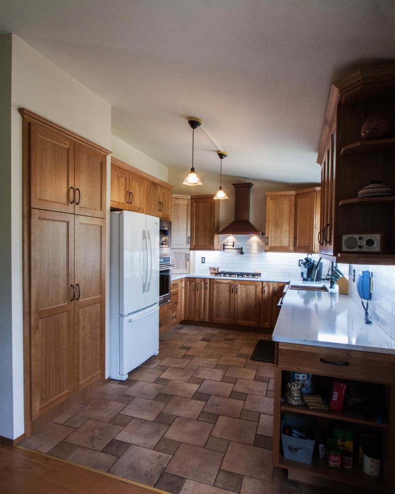 Klassisk inredning av ett litet kök, med en rustik diskho, luckor med infälld panel, bruna skåp, bänkskiva i kvarts, vitt stänkskydd, stänkskydd i keramik, klinkergolv i terrakotta och rött golv