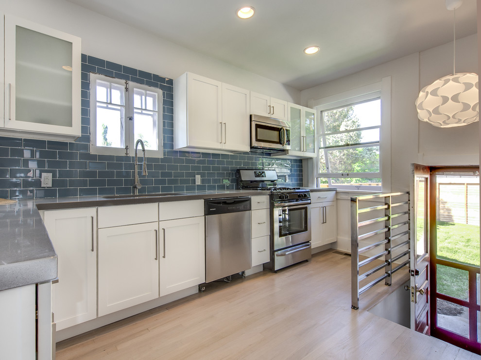 Imagen de cocina contemporánea con armarios estilo shaker, puertas de armario blancas, salpicadero azul, salpicadero de azulejos tipo metro y electrodomésticos de acero inoxidable