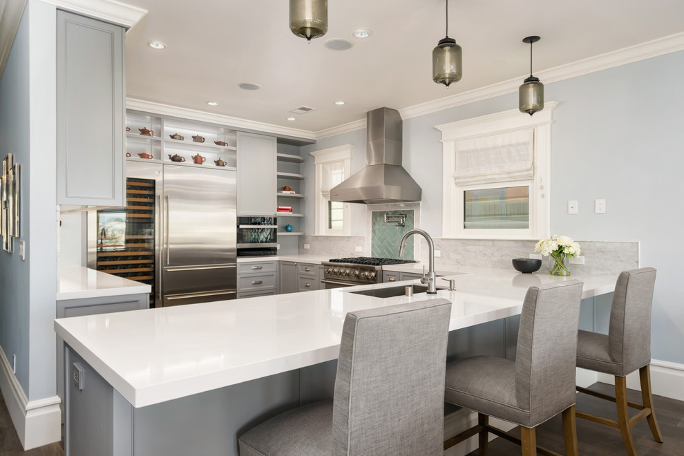 Large classic u-shaped open plan kitchen in San Francisco with a submerged sink, beaded cabinets, grey cabinets, engineered stone countertops, grey splashback, marble splashback, stainless steel appliances, dark hardwood flooring, a breakfast bar and brown floors.
