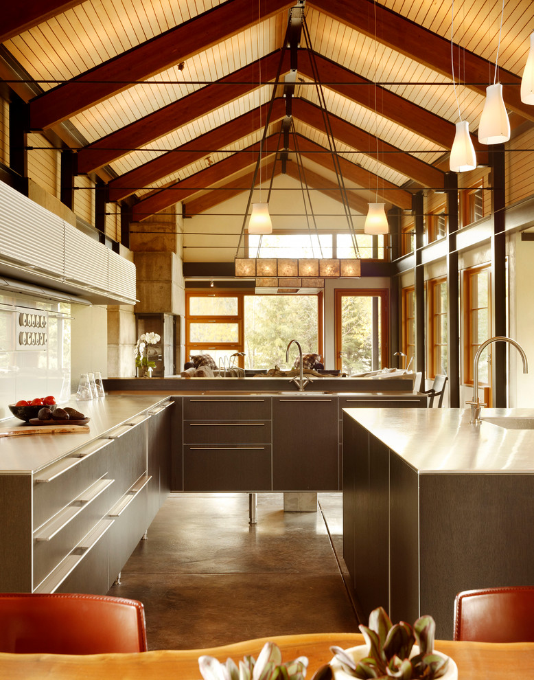 Photo of a contemporary open plan kitchen in Los Angeles with flat-panel cabinets, brown cabinets, stainless steel worktops, white splashback, glass sheet splashback and brown floors.