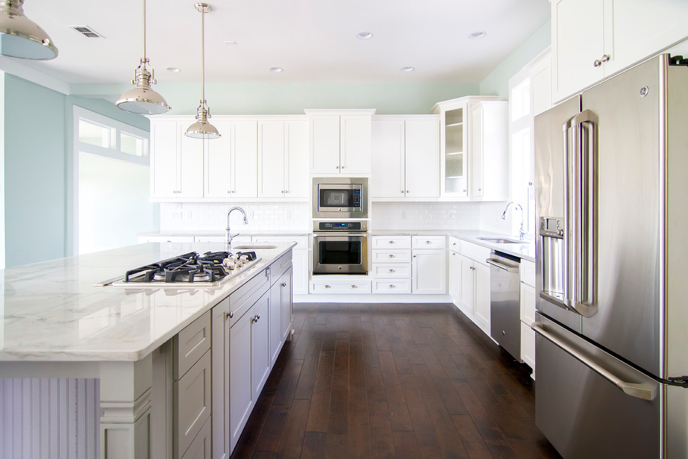 Eat-in kitchen - large coastal l-shaped dark wood floor and brown floor eat-in kitchen idea in Jacksonville with an undermount sink, shaker cabinets, white cabinets, marble countertops, white backsplash, subway tile backsplash, stainless steel appliances and an island