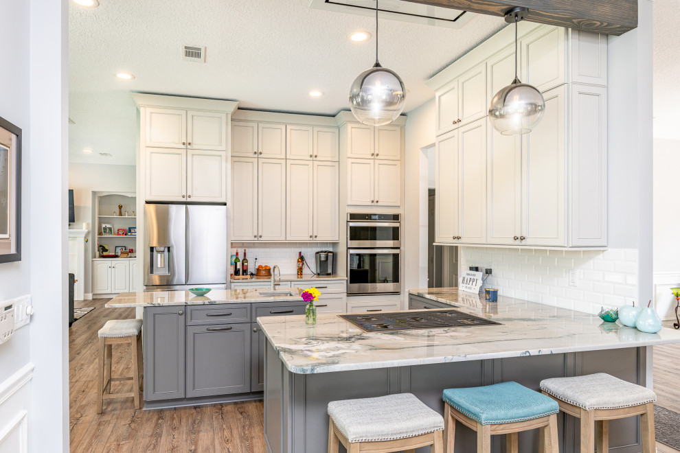 Kitchen - transitional u-shaped medium tone wood floor and brown floor kitchen idea in Jacksonville with an undermount sink, recessed-panel cabinets, white cabinets, white backsplash, subway tile backsplash, an island and white countertops