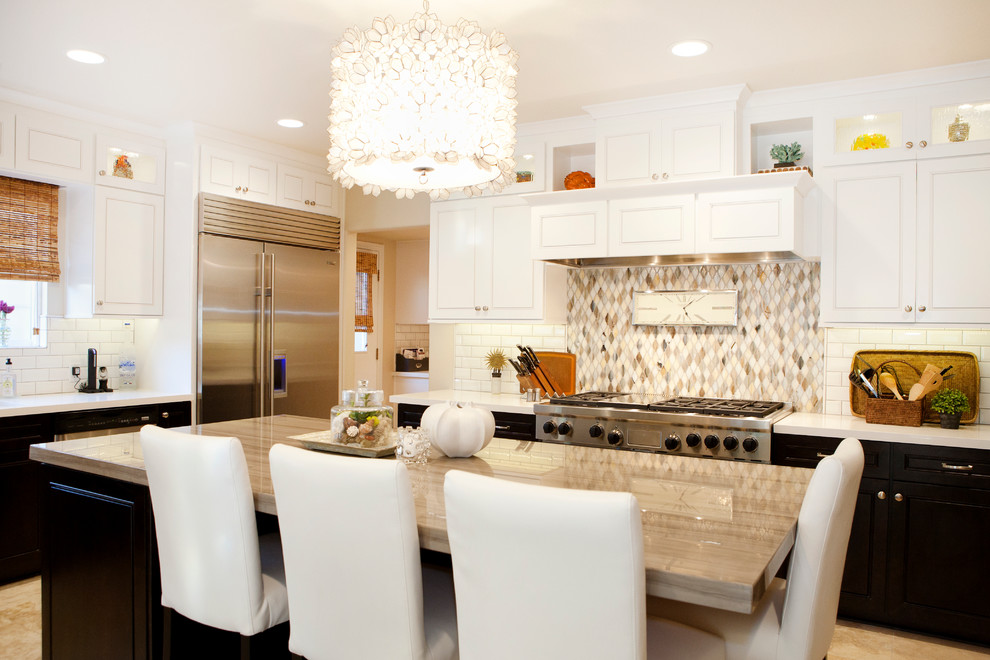 Eat-in kitchen - mid-sized transitional u-shaped limestone floor eat-in kitchen idea in Orange County with white cabinets, stainless steel appliances, an island, white backsplash and subway tile backsplash