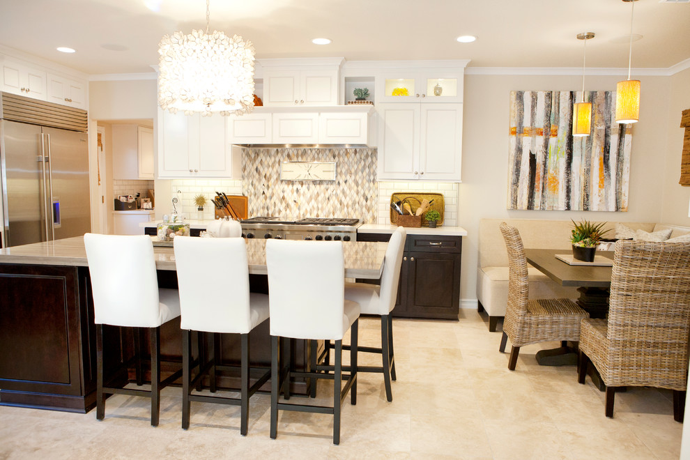 Inspiration for a mid-sized transitional u-shaped limestone floor eat-in kitchen remodel in Orange County with an island, white cabinets, stainless steel appliances, white backsplash and subway tile backsplash