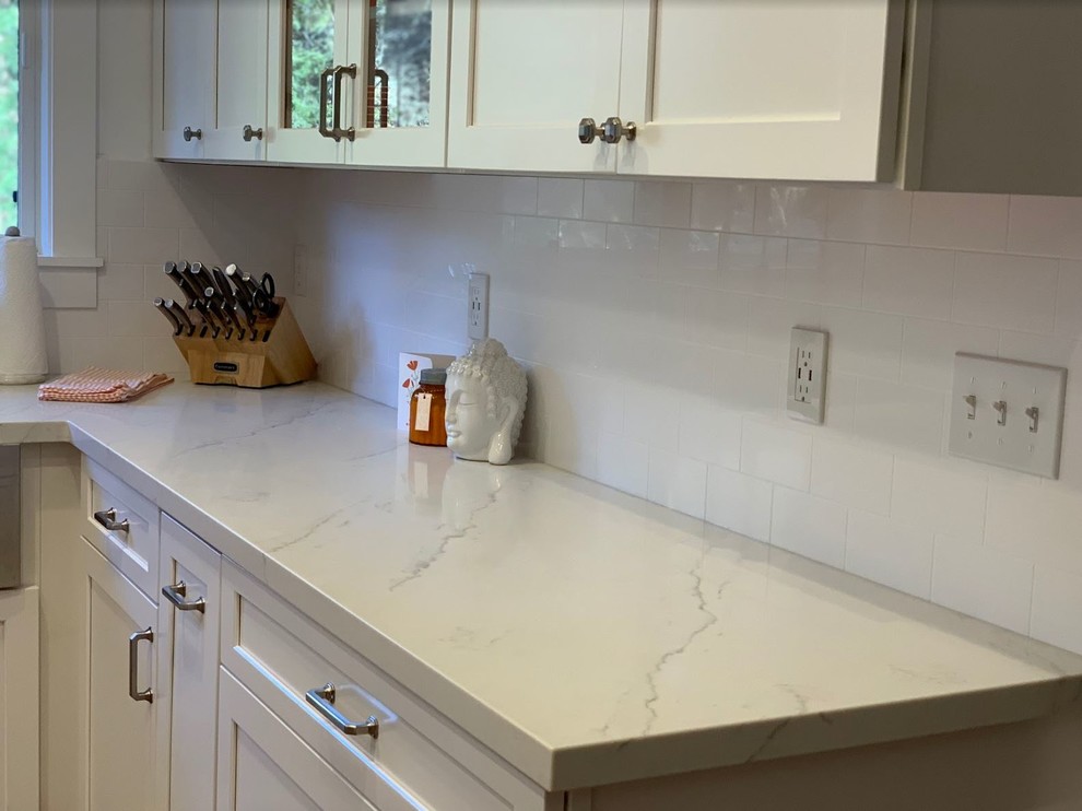 Foto på ett mellanstort rustikt vit kök och matrum, med en rustik diskho, luckor med upphöjd panel, vita skåp, bänkskiva i kvarts, vitt stänkskydd, rostfria vitvaror, en köksö och brunt golv