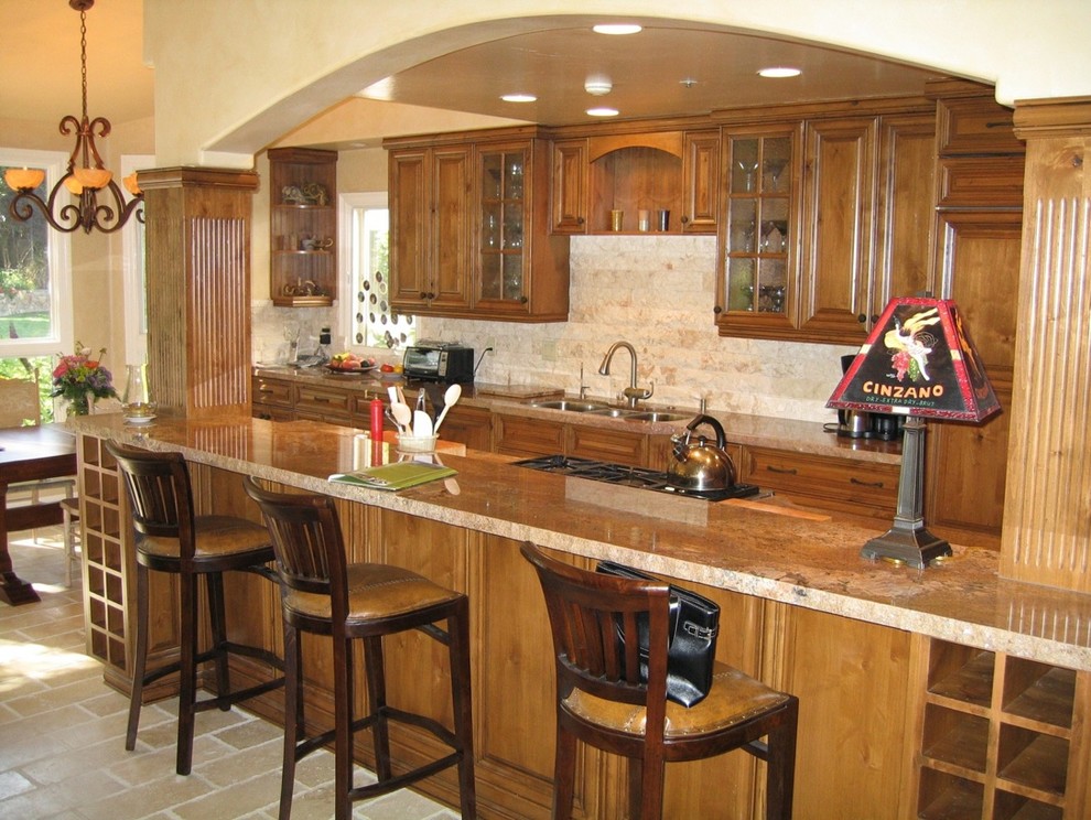 Inspiration for a timeless l-shaped open concept kitchen remodel in San Diego with a triple-bowl sink, raised-panel cabinets, distressed cabinets, granite countertops, beige backsplash, stone tile backsplash and paneled appliances