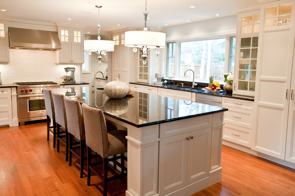 Kitchen - large contemporary u-shaped medium tone wood floor and brown floor kitchen idea in Calgary with an undermount sink, recessed-panel cabinets, white cabinets, granite countertops, white backsplash, subway tile backsplash, paneled appliances, an island and black countertops