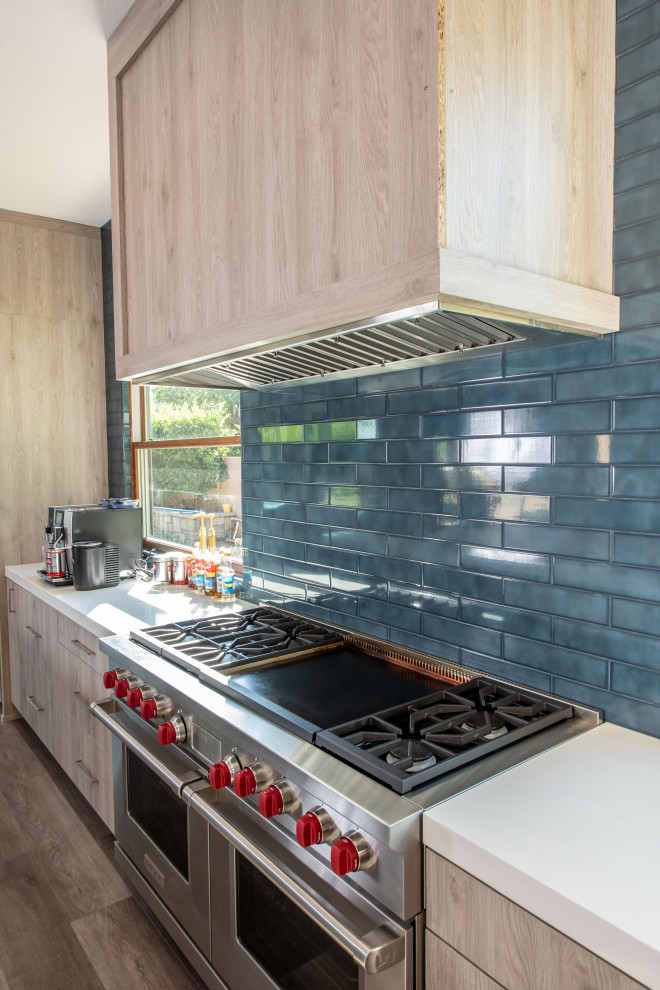 フェニックスにあるラグジュアリーな広いトランジショナルスタイルのおしゃれなキッチン (アンダーカウンターシンク、フラットパネル扉のキャビネット、淡色木目調キャビネット、珪岩カウンター、青いキッチンパネル、サブウェイタイルのキッチンパネル、シルバーの調理設備、クッションフロア、茶色い床、白いキッチンカウンター) の写真