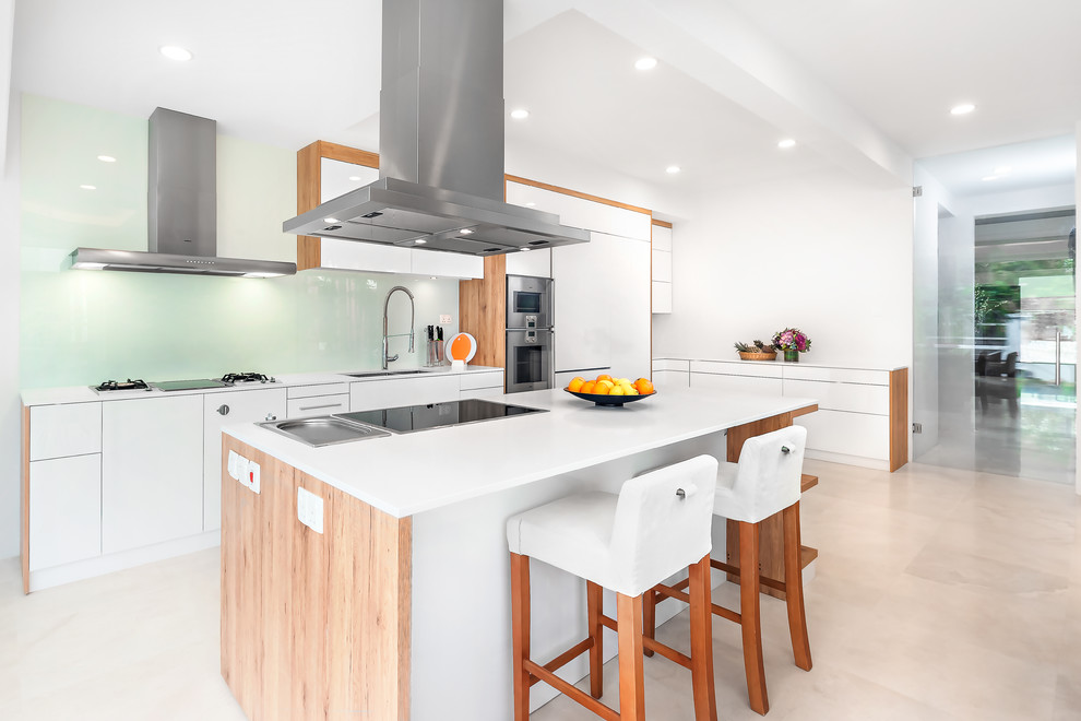 Exempel på ett stort modernt kök, med en undermonterad diskho, släta luckor, vita skåp, glaspanel som stänkskydd, rostfria vitvaror och en köksö
