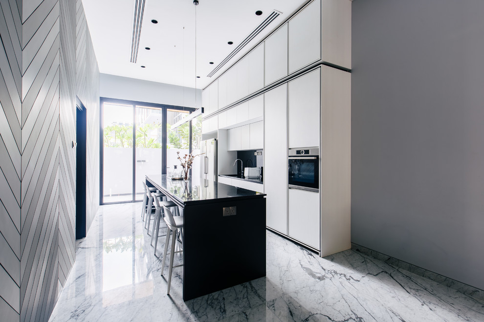 Design ideas for a contemporary single-wall kitchen in Singapore with flat-panel cabinets, white cabinets, stainless steel appliances, an island, grey floors and black worktops.