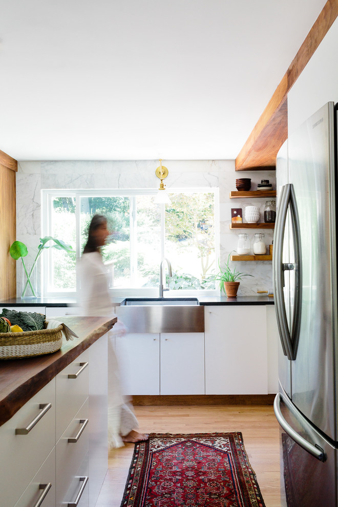 Exempel på ett litet modernt kök, med en rustik diskho, släta luckor, vita skåp, bänkskiva i täljsten, vitt stänkskydd, stänkskydd i stenkakel, rostfria vitvaror, ljust trägolv och en köksö