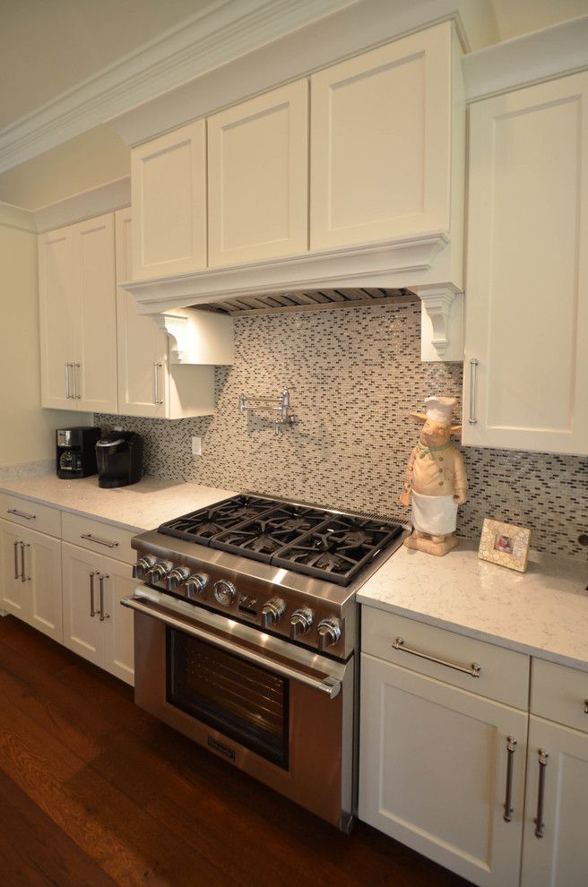 This is an example of a medium sized traditional single-wall open plan kitchen in New Orleans with a single-bowl sink, recessed-panel cabinets, white cabinets, stainless steel appliances, medium hardwood flooring and an island.